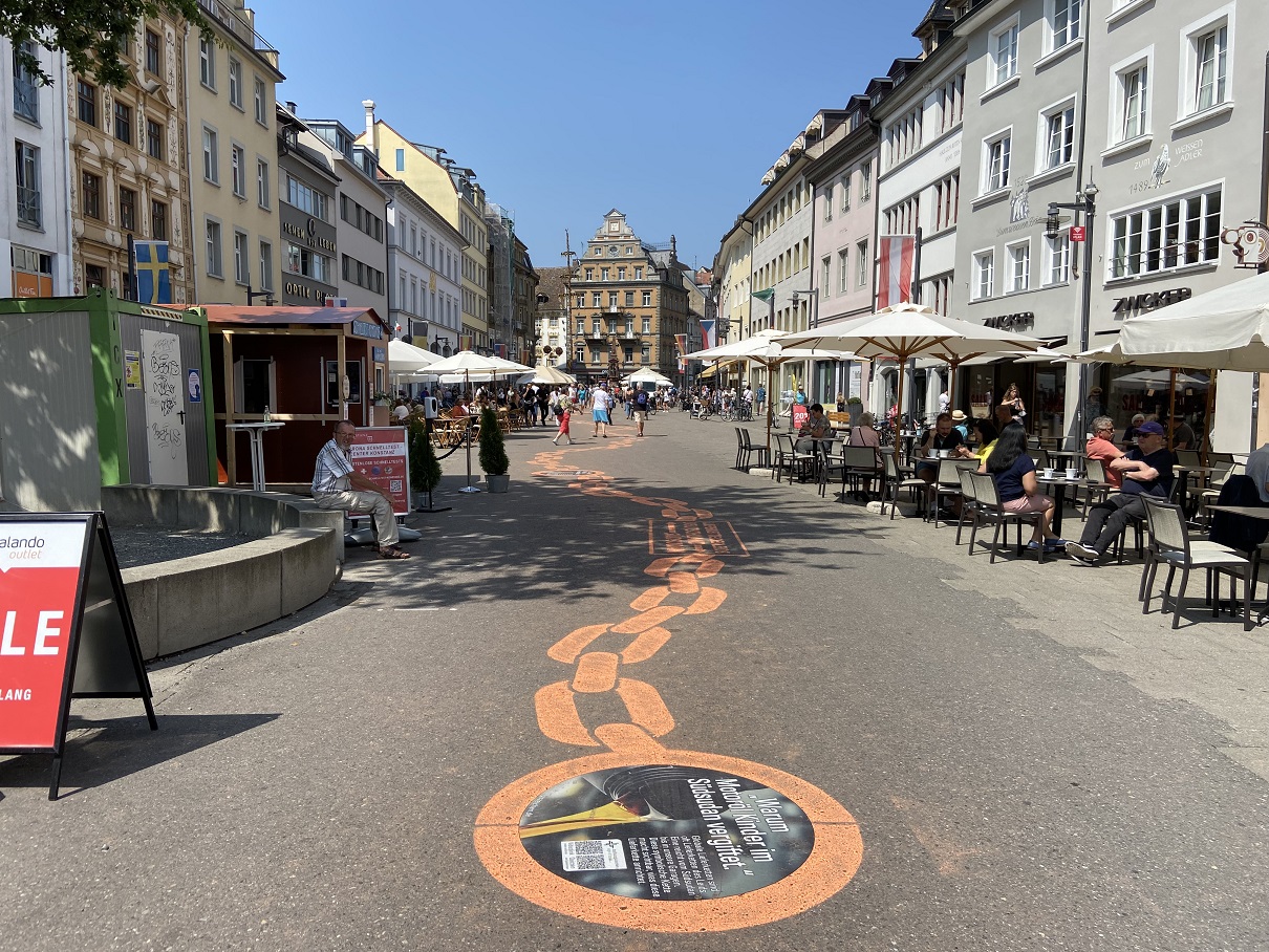 Die „Lieferkette des Leids&quot; verläuft zum einen auf der Marktstätte von Konstanz. Sie enthält neun Stationen mit QR-Codes, die zu Videos und einem Quiz führen.