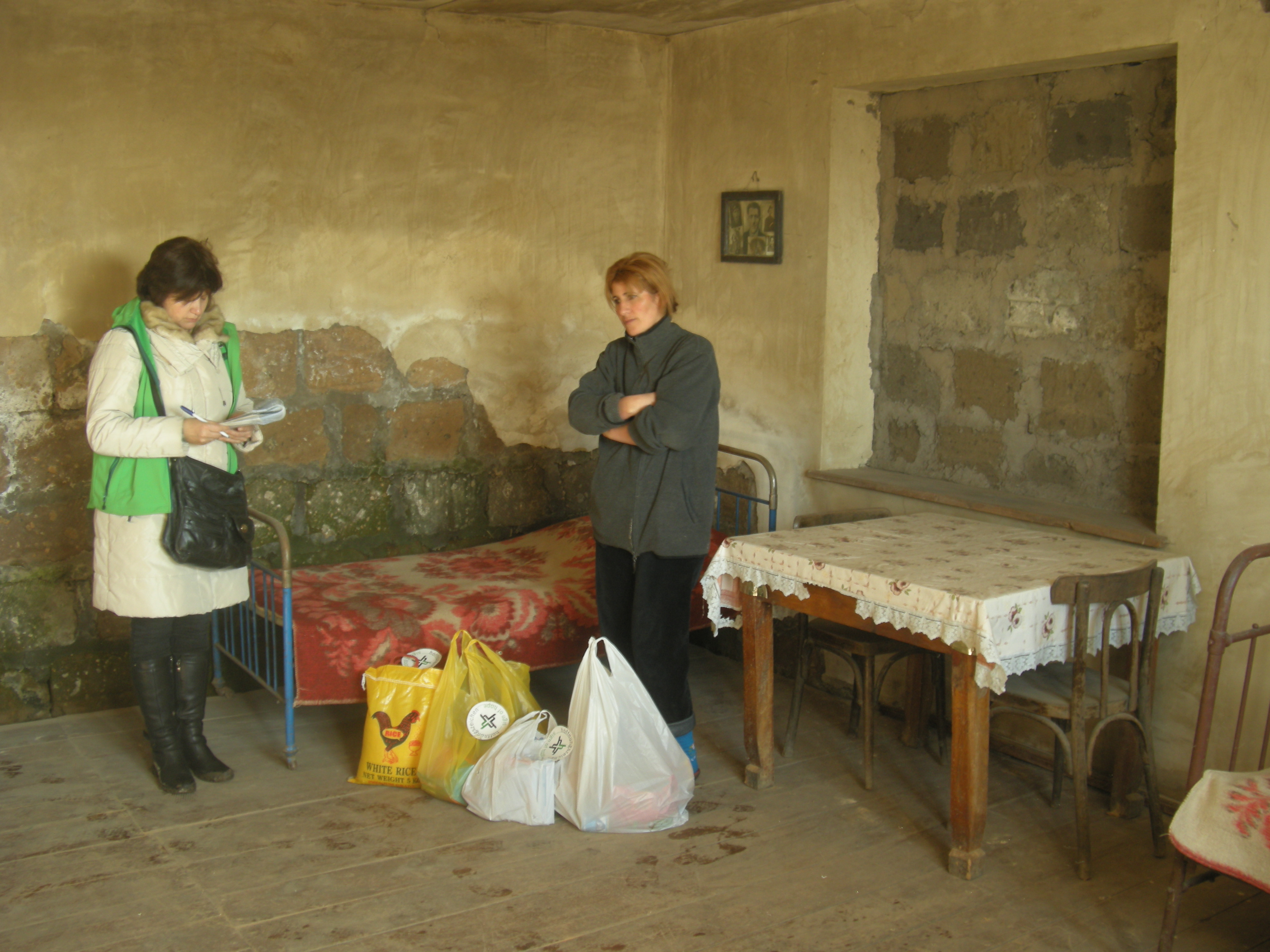 Alvard Avgjan (r.) musste fast alle Möbel veräußern, um Medikamente für ihren schwerkranken Mann kaufen zu können. Das Hilfspaket, das ihr unsere Mitarbeiterin Aljona Zeytunyan bringt, ist für sie eine große Entlastung.