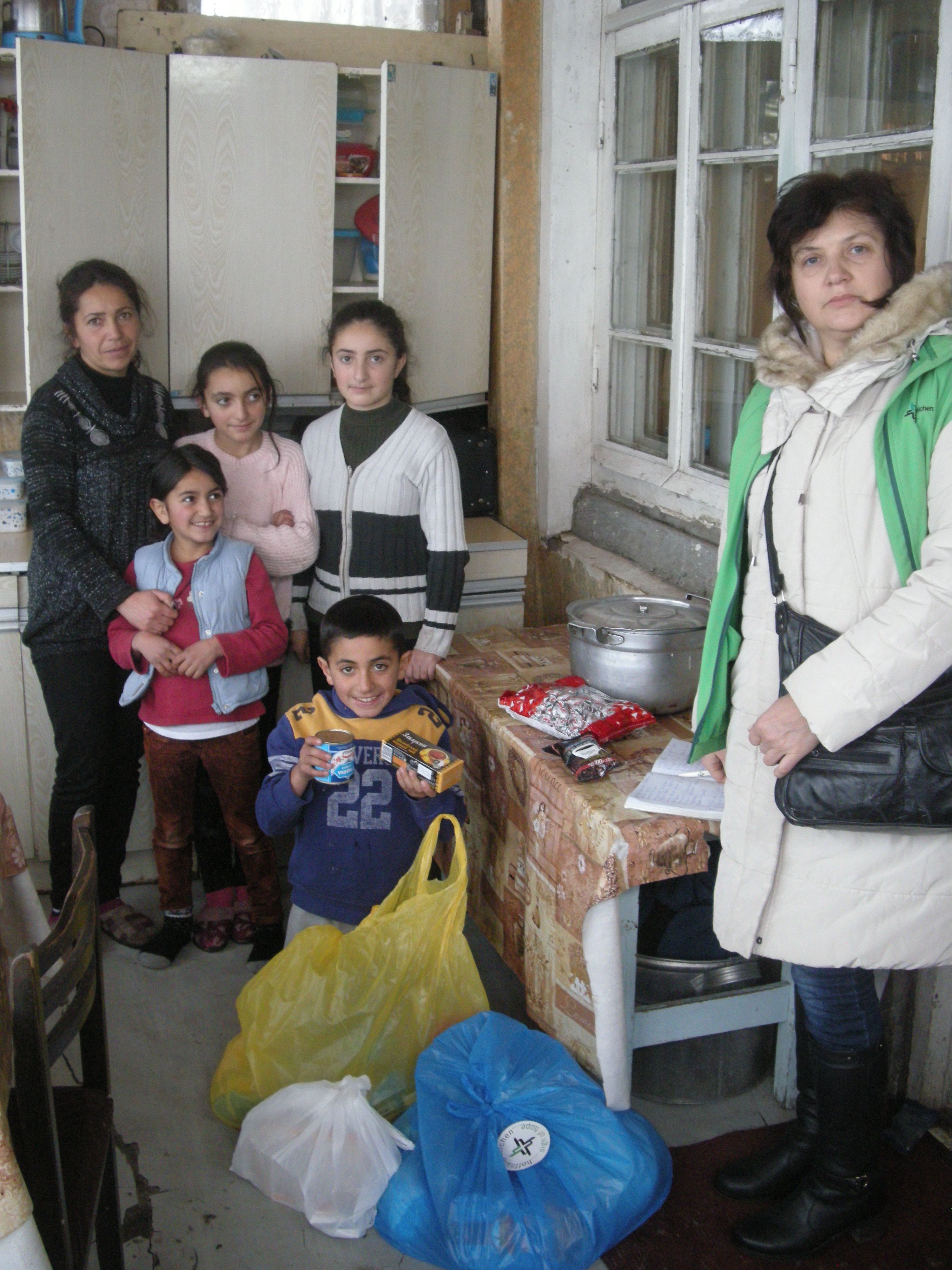 Die Kinder der Familie Harutjunjan sind beim Besuch unserer Mitarbeiterin Aljona Zeytunyan aufgeregt: Gäste mit so vielen Geschenken im Gepäck haben sie nicht alle Tage.