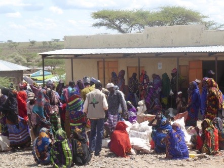 Viele Menschen machen sich auf den Weg zur Lebensmittelverteilung. Hoffnungszeichen-Mitarbeiter John Tuye sorgt für einen reibungslosen Ablauf.