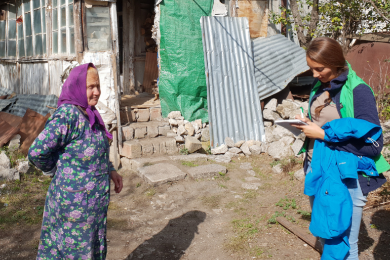 Sie steht vor den Trümmern, die sie ihr Zuhause nennt. Die 80-jährige Mariam Gnasian erzählt Hoffnungszeichen-Mitarbeiterin Ildiko Mannsperger von ihrem Leben in großer Armut.
