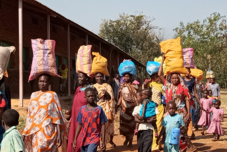 Wie in einer fröhlichen Prozession ziehen die Frauen und Kinder mit ihrem Hilfspaket nach Hause. Viele mangelernährte Kinder erhalten so dank unserer Spender  wieder ausgewogenere und nahrhaftere Mahlzeiten.