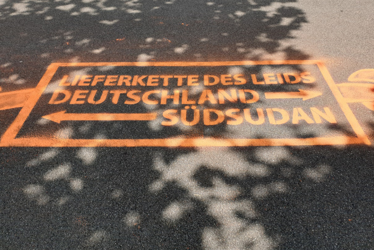 Wegweiser zeigen, wo die „Lieferkette des Leids" beginnt und endet.