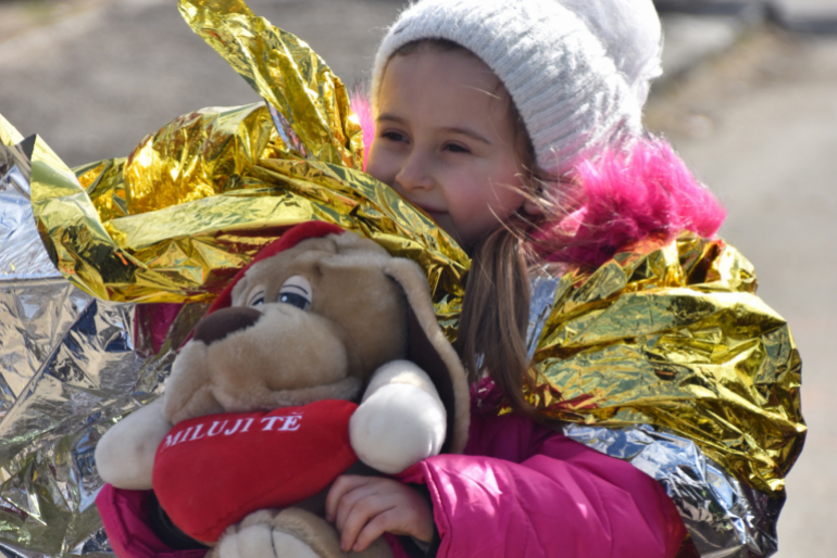 Ein geflüchtetes Mädchen erfreut sich an dem Glitzern einer goldglänzenden Wärmedecke.