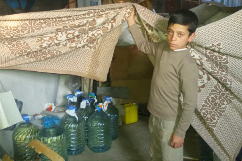 Ein Junge zeigt seine provisorische Unterkunft unter einer Brücke. Die Behausung besteht aus Decken und bietet daher keinen Schutz vor Kälte.