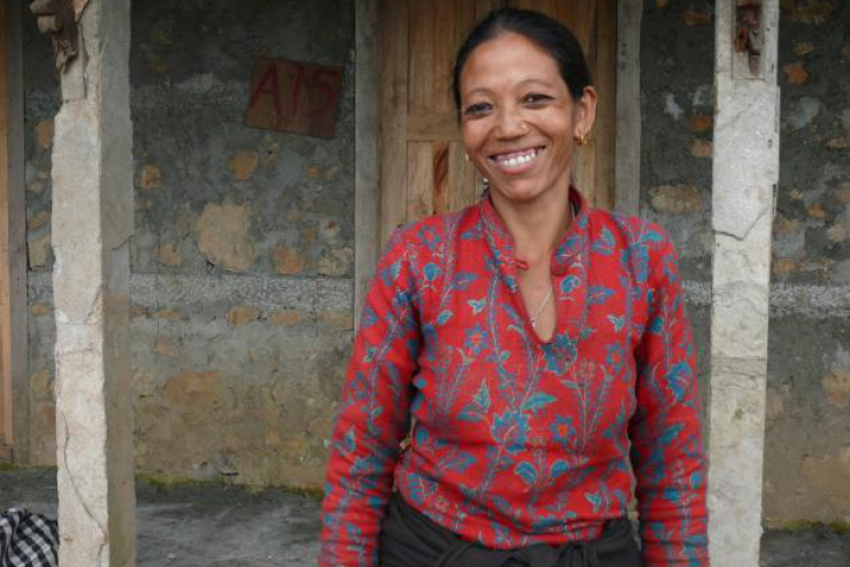 Sharmila steht stolz und glücklich vor ihrem neuen Zuhause. Wie Sharmila und Jhakendra hoffen auch andere Familien auf Unterstützung, um vor dem Wintereinbruch eine sichere Unterkunft zu erhalten.