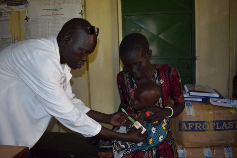 Behutsam untersucht Ernährungsberater Chol Ajuong seinen kleinen Patienten. Das spezielle Maßband verrät: Der Junge ist akut unterernährt.