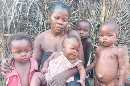 Ndumbala sitzt traurig und von ihrem Mann verlassen mit ihren Kindern vor ihrer selbst gebauten Hütte aus Palmzweigen am Rande des Dorfes Mondombe. Der Hunger ihrer Kinder bereitet der Frau große Sorgen.