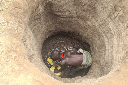 Ein Kind schöpft das letzte Wasser aus einem selbst gegrabenen Wasserloch. Es ist oft nicht sauber und verursacht Krankheiten.