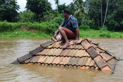 Ein Mann in Kerala rettet sich auf das Dach seines Hauses, das von den Fluten zerstört wurde.