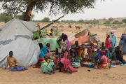 Sudanesische Flüchtlinge, die den Tschad überquert haben, versammeln sich in einem Lager neben einer behelfsmäßigen Unterkunft.