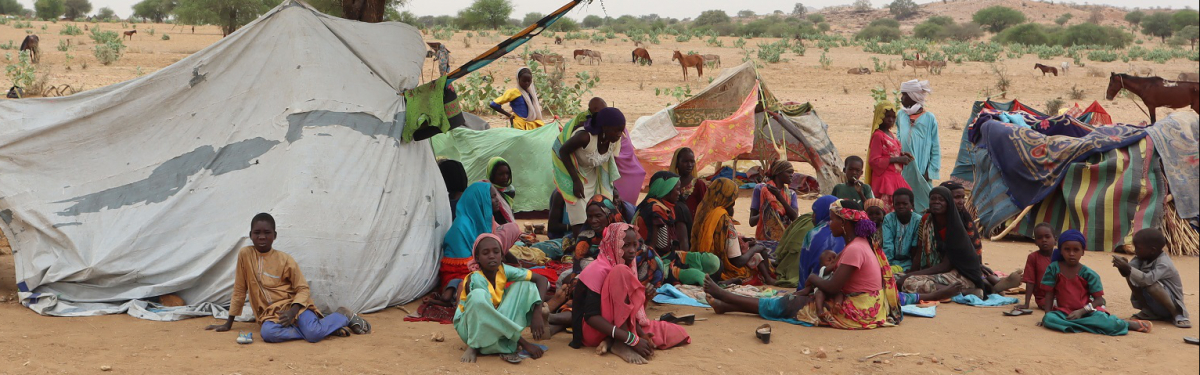 Sudanesische Flüchtlinge, die den Tschad überquert haben, versammeln sich in einem Lager neben einer behelfsmäßigen Unterkunft.