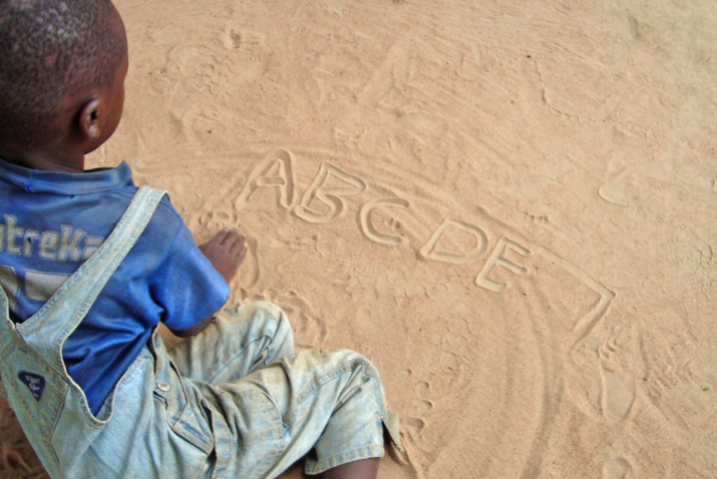 A child writes letters in the sand