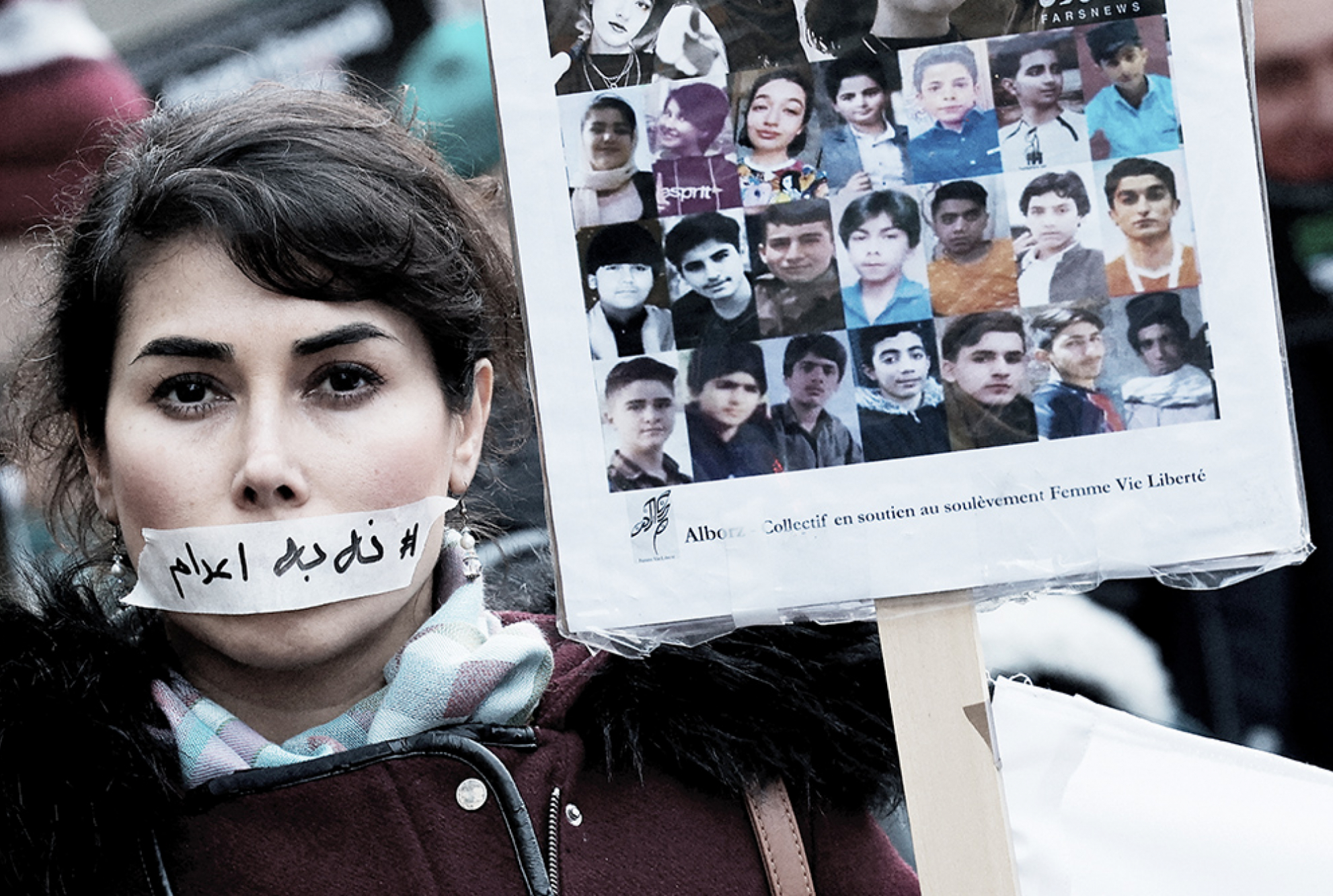 Eine Demonstrantin trägt am 31. Januar in Paris einen Aufkleber mit der Aufschrift „Keine Hinrichtung” über ihrem Mund, neben den Porträts mutmaßlicher Opfer von Razzien im Iran.